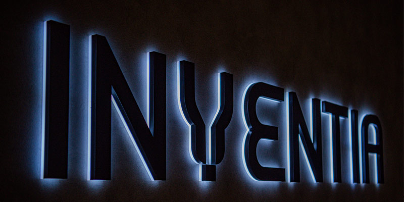 The word Inventia written in black letters with blue backlit light