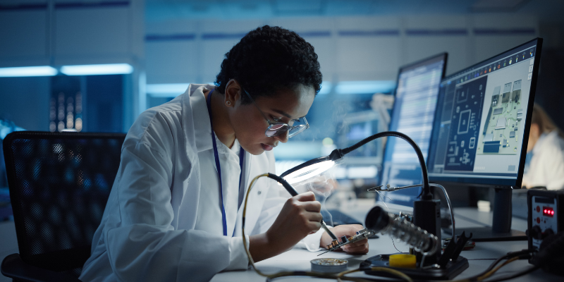 Male researcher in a lab coat studies object in computer lab