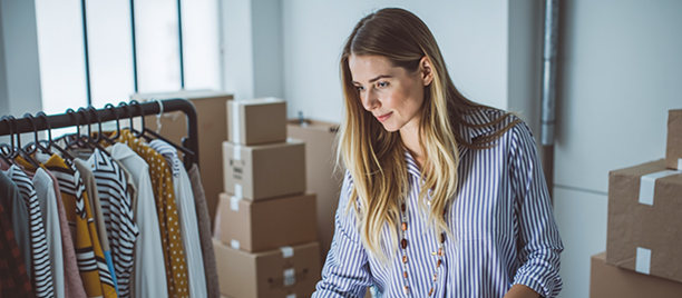 Woman uses her laptop as she packs boxes for delivery.
